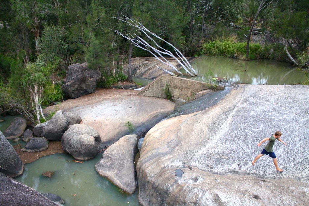 Word1 terms A man jumping across giant rocks and boulders in a gorge